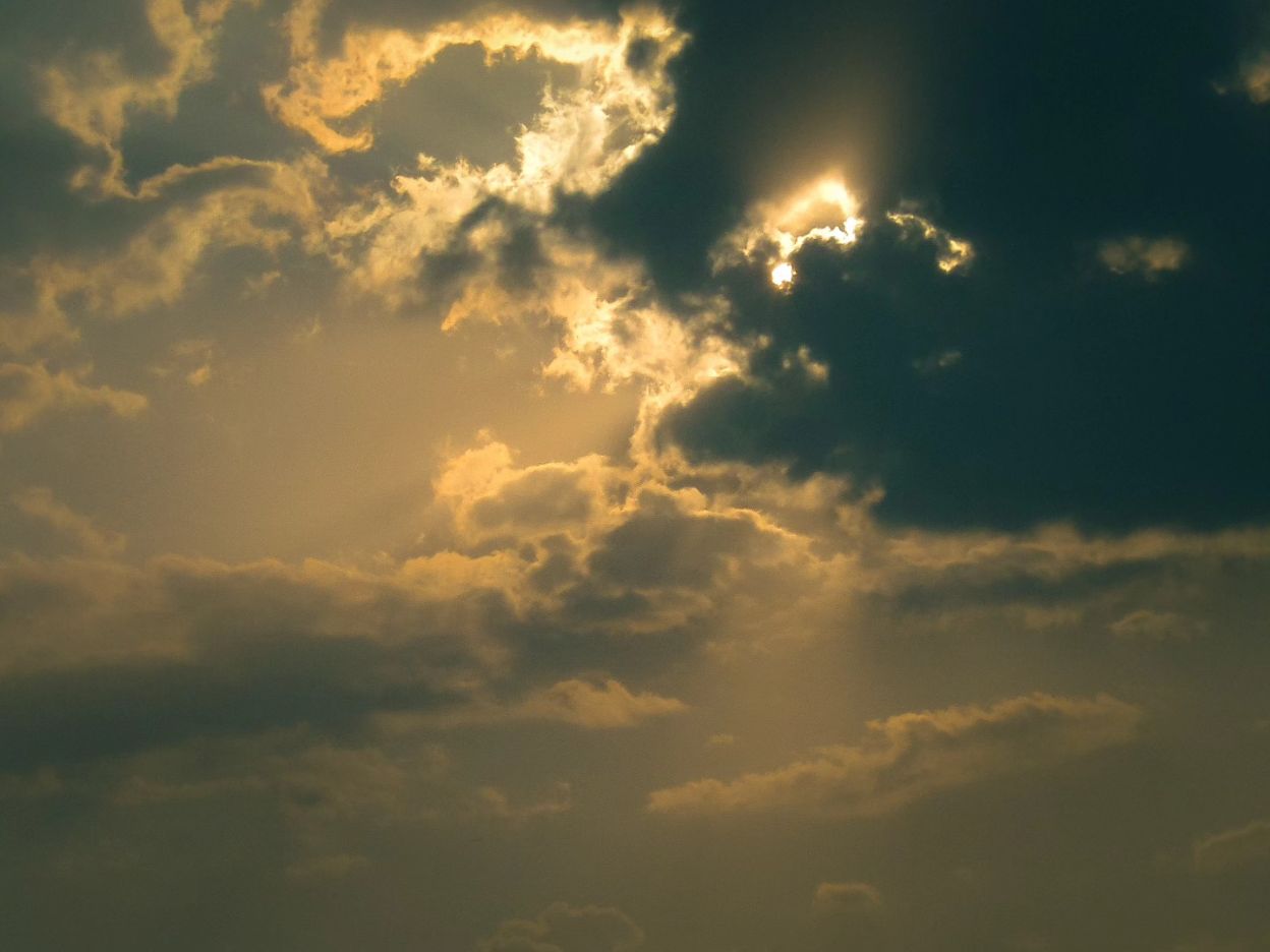 Golden sunlight cutting through layered clouds, photographed by CamEdict